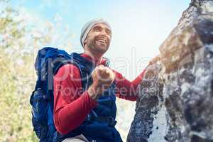 Every peak you ascend makes you stronger. Shot of a happy young hiker enjoying a mountain trail on his own.