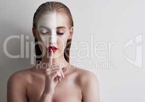 Beauty is art. Shot of a beautiful woman wearing face paint and red lipstick against a plain background.