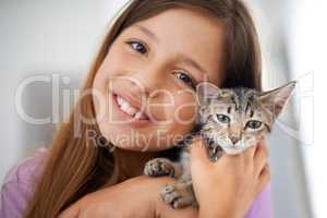 Can we keep him. A happy young girl holding a kitten affectionately.