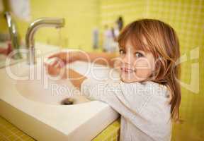 I can reach the tap now. A cute little girl washing her hands in the bathroom basin.