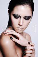 Intense beauty. Studio shot of a beautiful young woman wearing metallic-colored makeup and nail polish.