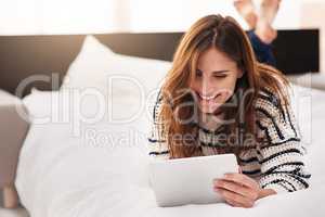 Unwinding online. Shot of a beautiful young woman using a digital tablet at home.
