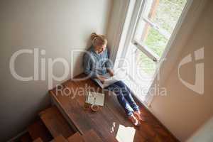 Using my laptop to work from home. A young woman sitting on a floor doing some researching on her laptop.