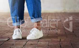 Shoes on, lets dance. Cropped shot of an unrecognizable person standing on a brick floor while wearing white sneakers and blue jeans.