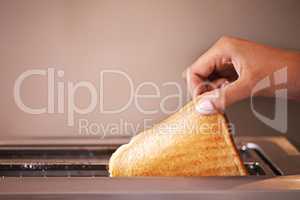 Golden brown and ready to munch. Cropped shot of a woman taking toast out of a toaster.