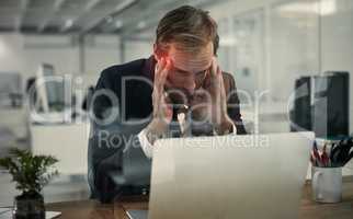 Brain overload. Shot of a businessman looking stressed while working at his laptop.