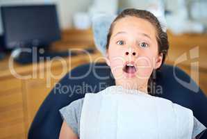 In the hot seat. Shot of a young girl looking terrified while sitting in a dentists chair.