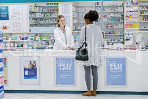 Let us help you fight the winter blues. Rearview shot of a young woman purchasing over the counter medication from a female pharmacist.