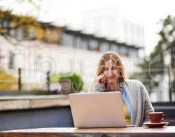 Fresh air and free wifi. Cropped shot of an attractive young woman using her laptop at an outdoor coffee shop.