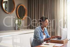 Managing pregnancy and her monthly bills. Shot of a pregnant young woman using a laptop while working from home.