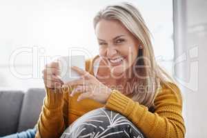 For a relaxing time at home just add coffee. Portrait of an attractive mature woman enjoying a beverage while relaxing on the sofa at home.