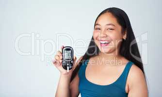 I aced my blood sugar test. Studio portrait of a young girl using a blood sugar test against a gray background.