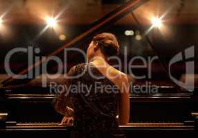 Performing for the audience. Shot of a young woman playing the piano during a musical concert.