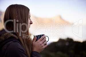 Enjoying some coffee in the mountains. Shot of an attractive young woman enjoying a hot drink while on a hike.