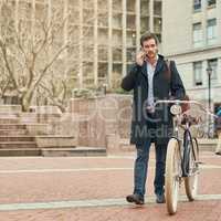 En route to work through the city. Portrait of a young businessman commuting to work with his bicycle.
