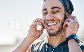 The groove is getting him into the fitness zone. Shot of a sporty young man listening to music while exercising outdoors.