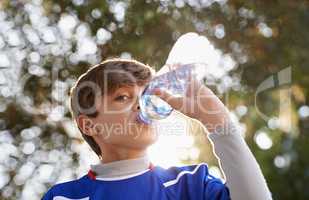 Boys will be boys. Shot of a young boy in sports clothing drinking from a water bottle.