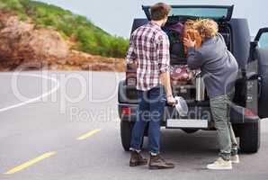 We need a bigger truck. Shot of a two people stopped at the side of the road and repacking their truck.