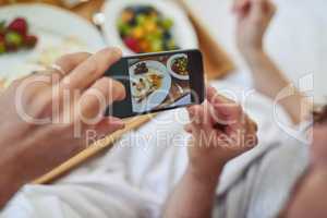 Look a this amazing breakfast youve made. PoV shot of an unrecognizable couple taking a photo of their breakfast that theyre having in bed during morning hours.