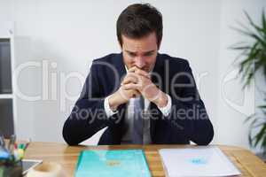 Struck by indecision. Shot of a nervous looking businessman sitting at a desk trying to decide on which report to use.