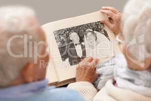 Remembering like it was yesterday. Shot of a senior couple leafing through their wedding album.