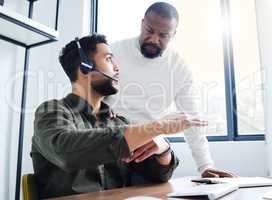 Well solve this together. Shot of a young male call center worker receiving direction from his boss.