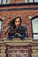 Giving you a piercing gaze. Seductive young woman in a black catsuit looking at you from a rooftop.