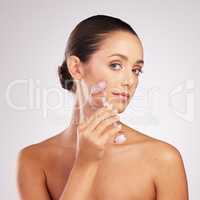 This is how my skin care rolls. Shot of an attractive young woman using a jade roller on her face against a studio background.