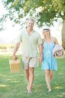 Weve planned the perfect picnic. A happy couple walking in the park looking for a spot to set up their picnic.