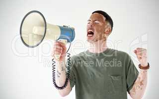 Speak up, even if your voice shakes. Studio shot of a young man with vitiligo using a megaphone against a white background.