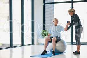 Lets lift this up a little higher. Full length shot of a friendly female physiotherapist helping her senior patient work out with weights.