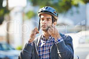 Strap in for safety. Shot of a handsome young man preparing to take a ride by putting on a helmet.