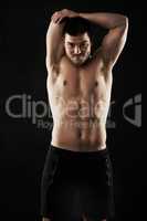 Your limits are smaller than you think so keep pushing. Studio portrait of a sporty young man stretching his arms isolated on black.