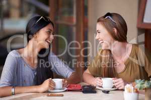 Catching up over coffees. Two attractive young woman enjoying a coffee at a bistro.