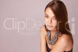 Beauty and elegance. Beautiful young woman wearing a beaded necklace against a pink background.