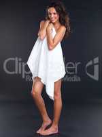 Naturally beautiful. Studio portrait of a beautiful young woman holding a towel to cover herself while standing against a black background.