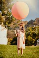Any bigger and it would carry me away. Portrait of a cute little girl holding a huge balloon while standing outside.