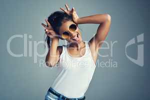 Showing off her quirky side. Studio portrait of a beautiful young woman gesturing with bunny ears against a grey background.