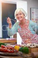 Tastes like home cooking. Shot of a senior woman tasting the food she is cooking.