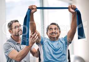Hes raising the bar today. Shot of a senior man exercising with a resistance band during a rehabilitation session with his physiotherapist.