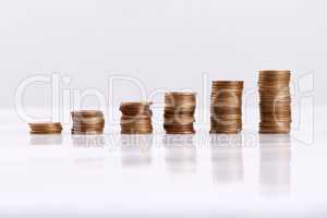 Every little bit helps. Studio shot of columns of coins isolated on a white background.