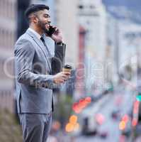 Leave the negotiations to me. Shot of a handsome young businessman standing alone and using his cellphone while enjoying a cup of coffee.