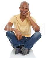 Hes comfortable in any situation. Studio portrait of a friendly African-American man sitting cross-legged with his hand to his chin.