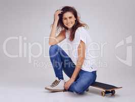 Have wheels will travel. Studio portrait of an attractive young woman sitting on the floor with a skateboard.