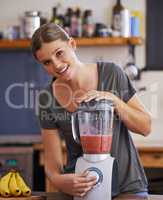 Making it oh so smooth. Portrait of an attractive young woman preparing a fruit smoothie.