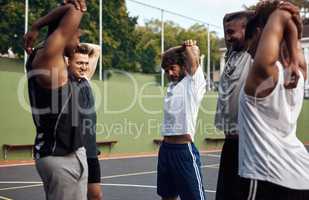 Got to warm up before we shoot some hoops. Shot of a group of sporty young men stretching their arms on a sports court.