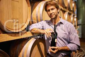 The right wine for every occasion. Portrait of a handsome mature man standing in a wine cellar with a bottle of wine.