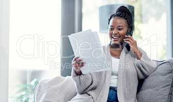 Great financial advice is just a call away. Shot of a young woman going over paperwork and using a smartphone on the sofa at home.