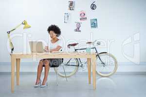 Shot of an attractive young woman sitting at her workstation in the office. The commercial designs displayed in this image represent a simulation of a real product and have been changed or altered enough by our team of retouching and design specialists so