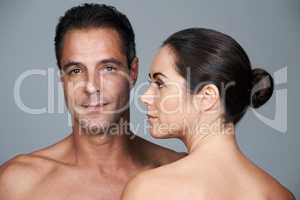 Body conscious couple. Studio portrait of a mature couple standing close together against a gray background.